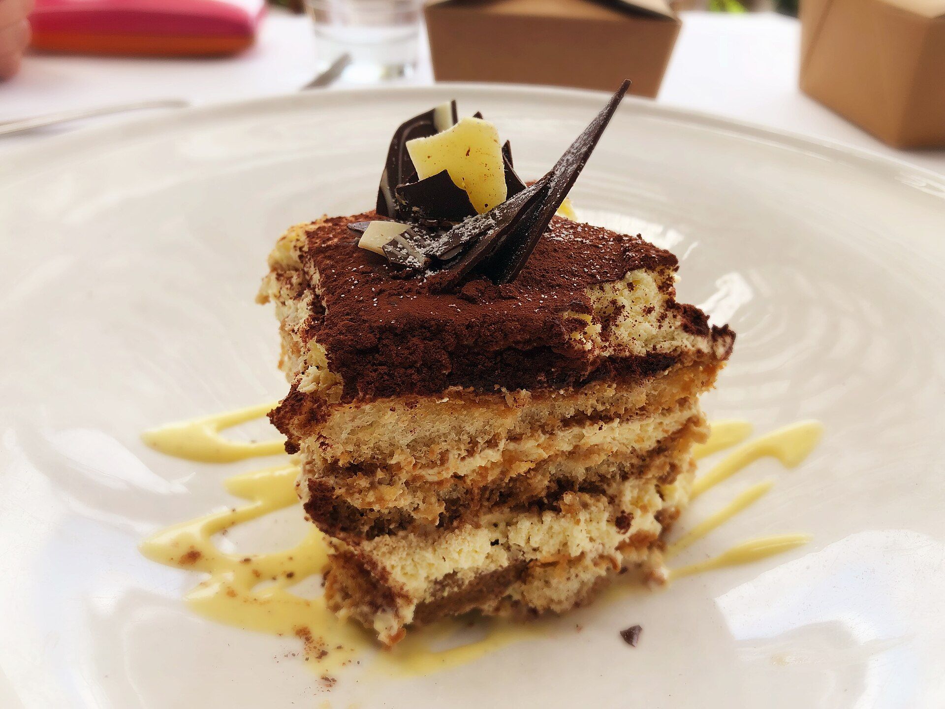 Une part de tiramisu en couches, cacao et copeaux de chocolat